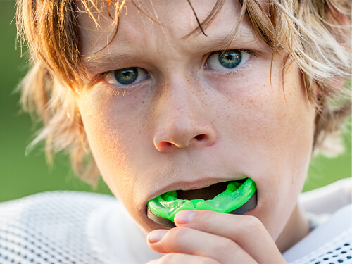 Young boy wearing green athletic mouthguard
