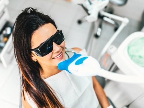 Woman getting professional teeth whitening in dental office