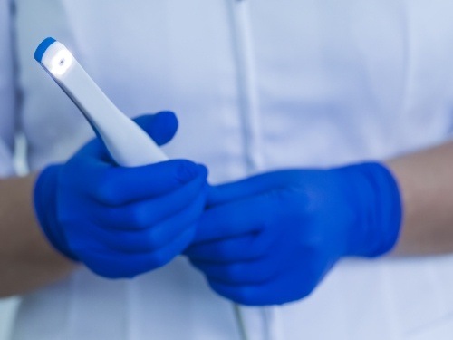 Dental team member holding thin white intraoral camera