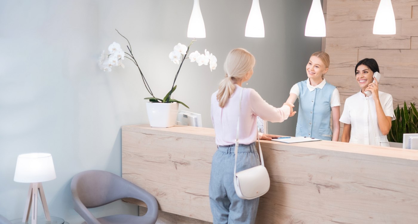 Woman shaking hands with dental receptionist