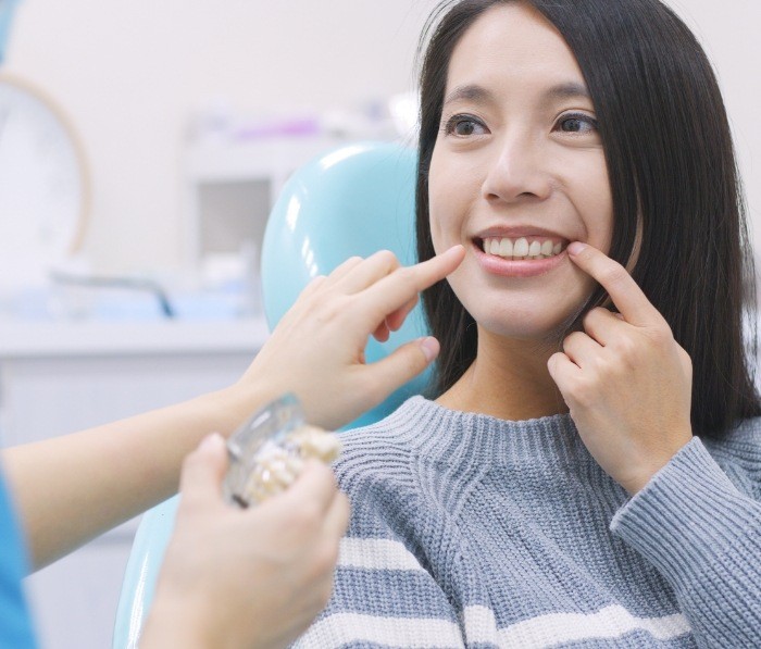 Woman pointing to her smile during preventive dentistry visit