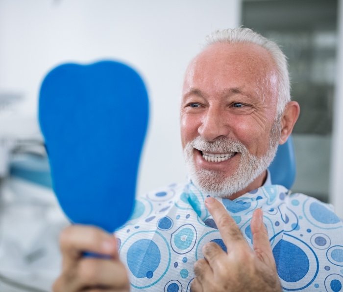 Senior man looking at his smile in mirror
